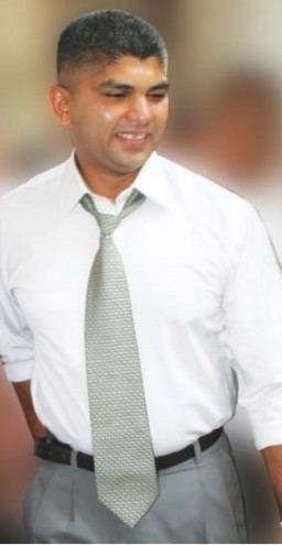 Lohan Ratwatte smiling and wearing a white long-sleeved shirt along with gray pants and necktie.