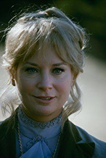 Lois Nettleton smiling with blonde curly hair while wearing a black and blue blouse