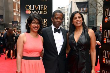 Lolita Chakrabarti smiling and wearing a black gown, Indhu Rubasingham wearing a pink dress, while Adrian Lester wearing black coat, long sleeves, and bow tie