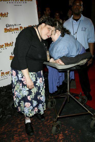 George Schappell wearing a black top and a floral skirt while Lori  Schappell wearing a denim dress.