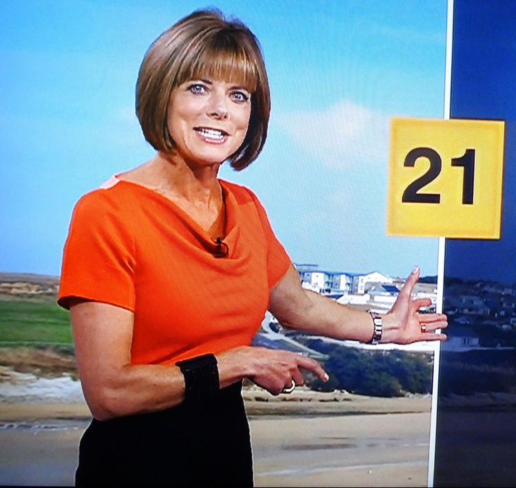 Louise Lear at work as a BBC weather presenter wearing red blouse and black skirt