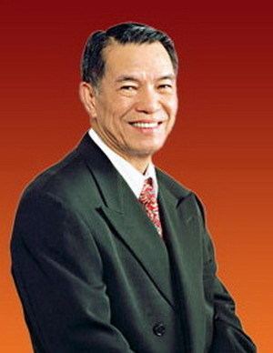 Lucio Tan smiling while wearing black coat, white long sleeves and neck tie