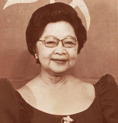Lucrecia Roces Kasilag smiling, with short hair, wearing earrings, eyeglasses, and a black Filipiniana dress.