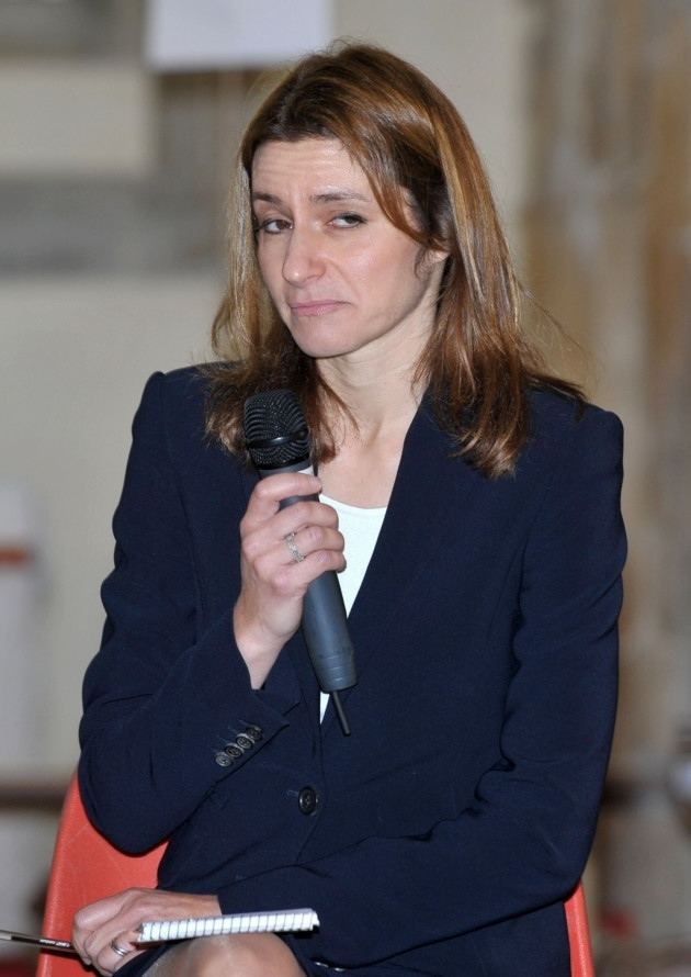 Lucy Frazer wearing a black coat while holding a microphone