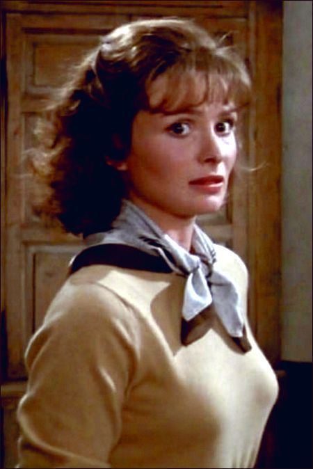Lucy Gutteridge with a shocked face while wearing a beige long sleeve blouse and ribbon scarf in a scene from the 1984 film, Top Secret!