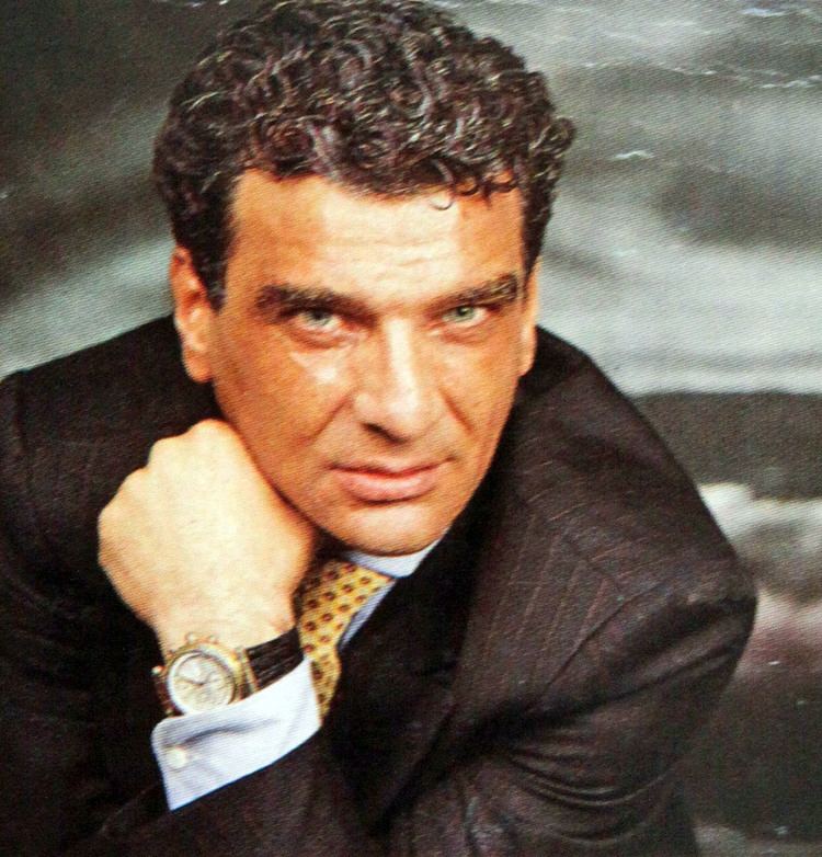 Luigi Giuliano wearing black coat, long sleeves, neck tie and wrist watch