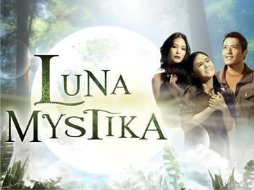 The movie poster of Luna Mystika 2008, in a Enchanted forest with a large moon, plants and trees, at left is the title written “LUNA MYSTIKA” at the right, from left Heart Evangelista is serious has, long hair wearing black dress, in the middle  Heart Evangelista is smiling, standing looking up,hands together to her chest has long black hair and scar on her face, wearing a brown long blouse, at the right, Mark Anthony Fernandez is smiling, looking up. Standing has black hair wearing an orange shirt under a brown polo.