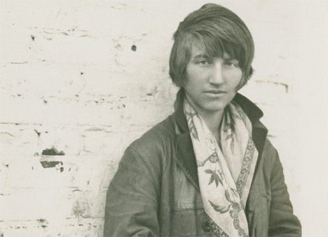 Black and white photo of Lutah Maria Riggs with short hair, wearing a jacket and a scarf.