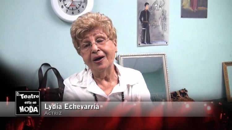 Lydia Echevarría, in one of her interviews, wearing a white blouse, earrings, and eyeglasses