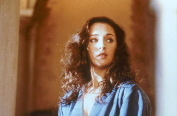 Lydie Denier looking at the side, with curly hair, and wearing a blue blouse