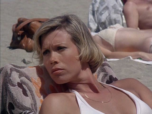 Lynette Mettey with short blonde hair, wearing necklace and white swimsuit ...