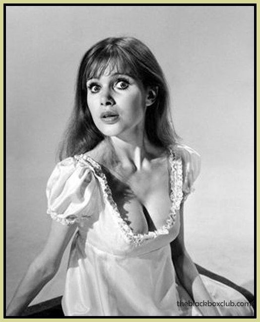 Madeline Smith with a shocked face while wearing a dress