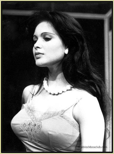 Madeline Smith wearing a sleeveless top, pearl necklace, and earrings
