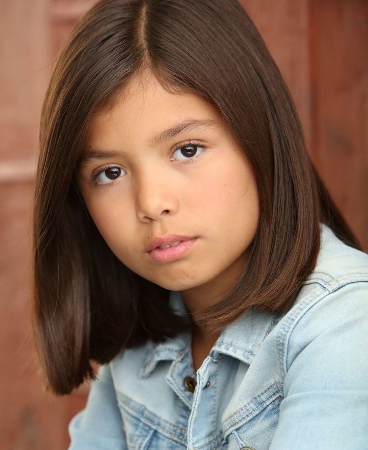 Madelyn Miranda with a serious face, with short hair, and wearing a denim polo shirt.