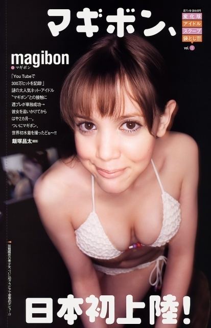 Magibon with a tight-lipped smile while wearing a white bikini with a caption written in the Japanese language