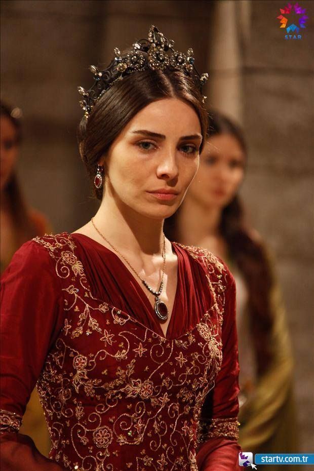 Meryem Uzerli plays role of Mahidevran wearing a crown and a red dress in "Muhtesem Yuzyil"