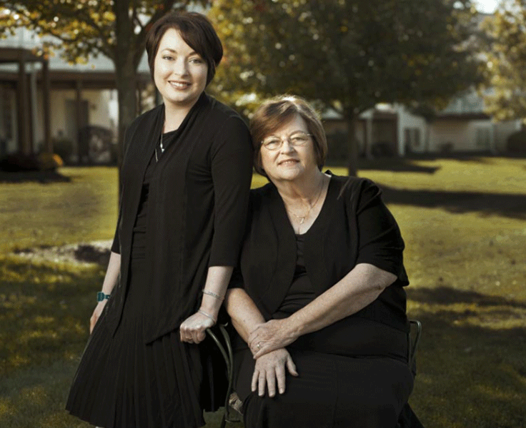 Mahtob Mahmoody smiling while sitting on the chair and wearing a black  dress and her mother Betty Mahmoody also wearing a black dress