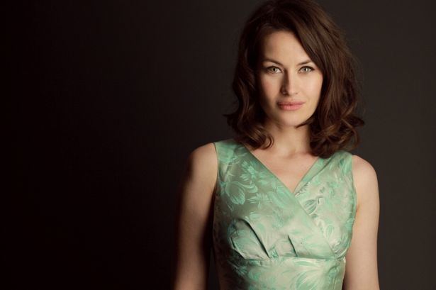 Maimie McCoy smiling while wearing a green dress