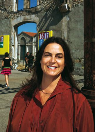 Maja Hoffmann smiling, with wavy hair, wearing a necklace, and a red blouse.