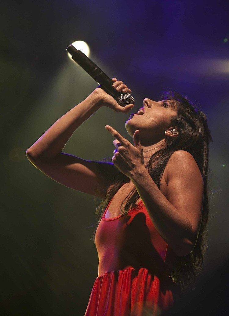 Mala Rodríguez while performing on stage wearing a red sleeveless dress