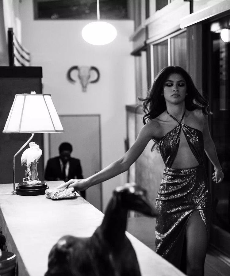 Zendaya holding a pouch while wearing a shiny sultry gown in a scene from the 2021 American black-and-white romantic drama film, Malcolm & Marie