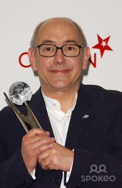 Malcolm Hebden smiling in a ceremony while holding an award and wearing formal attire.
