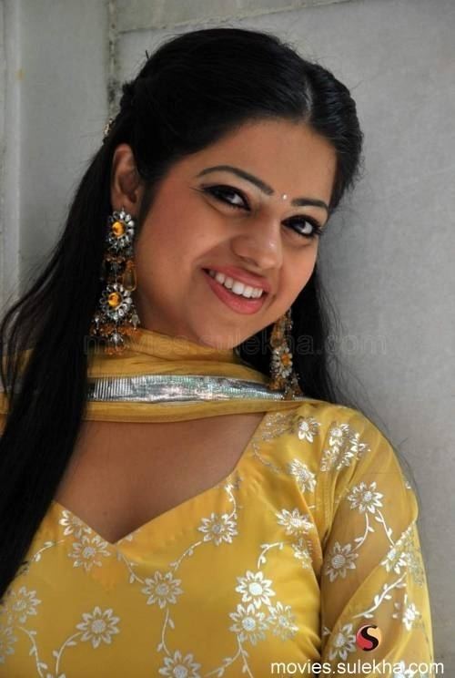 Mallika wearing earrings, a yellow scarf, and a yellow dress.