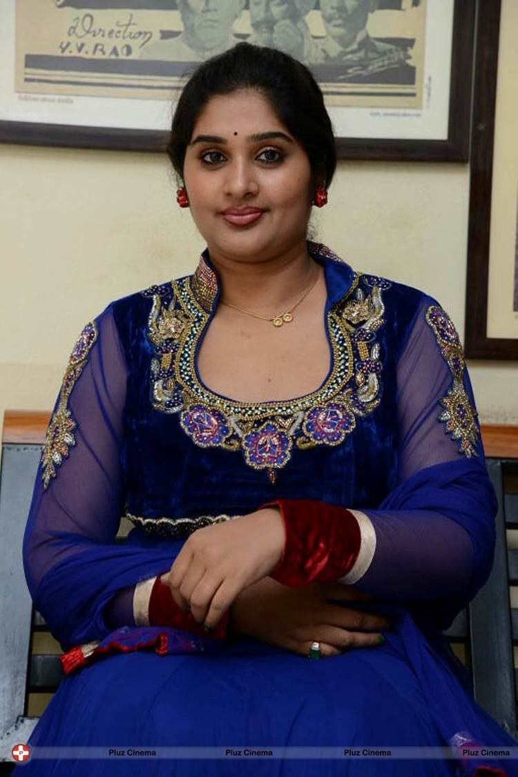 Mamilla Shailaja Priya smiling and wearing a blue and gold dress as well as red earrings.