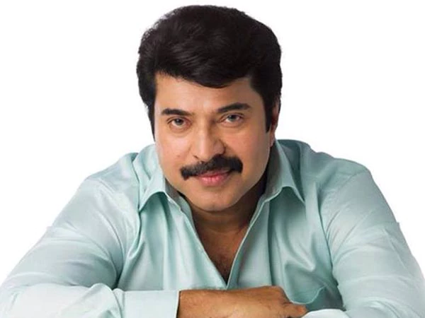 Mammootty smiling while wearing a light blue-green long sleeves