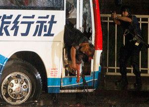 Policemen check the body of the hostage-taker on the shattered door of the hijacked bus in Manila
