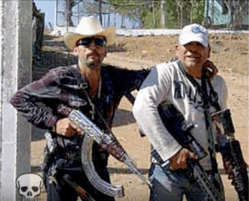 Manuel Torres Félix holding a gun with a man beside him