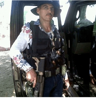 Manuel Torres Félix wearing a black vest and holding a gun
