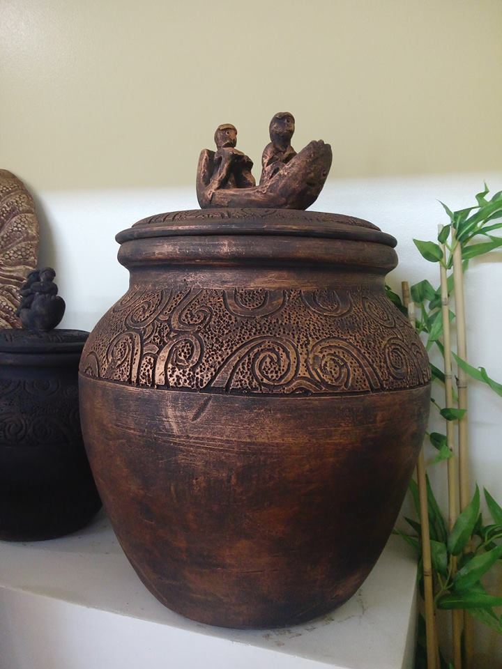 A brown Manunggul Jar beside a plant.