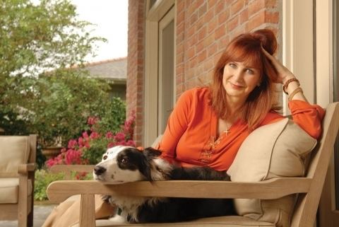 Margaret Orr smiling while sitting on the couch beside her dog