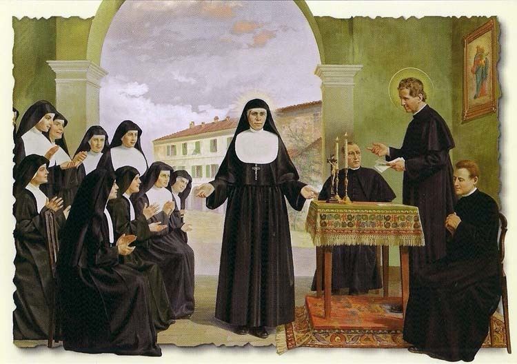 Maria Domenica Mazzarello (center) together with 10 Salesian Sisters on her right sitting while others are standing with open hands and 3 priests on her left, with candles on the table on a red carpet in front of the 3 priests with a house in the background. Maria standing in the middle with open hands is wearing black shoes, a white head cover under a black nun veil clothing, a long cross necklace under a religious nun habit clothing, and the Salesian Sisters are wearing the same as Maria, and the Priest is wearing a black cassock