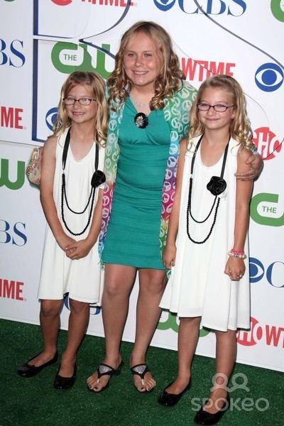 Maria Lark smiles while taking a picture with her twin fans wearing a green dress
