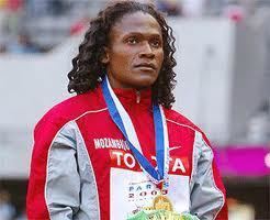 Maria Mutola looking afar while wearing a red and gray jacket and medal