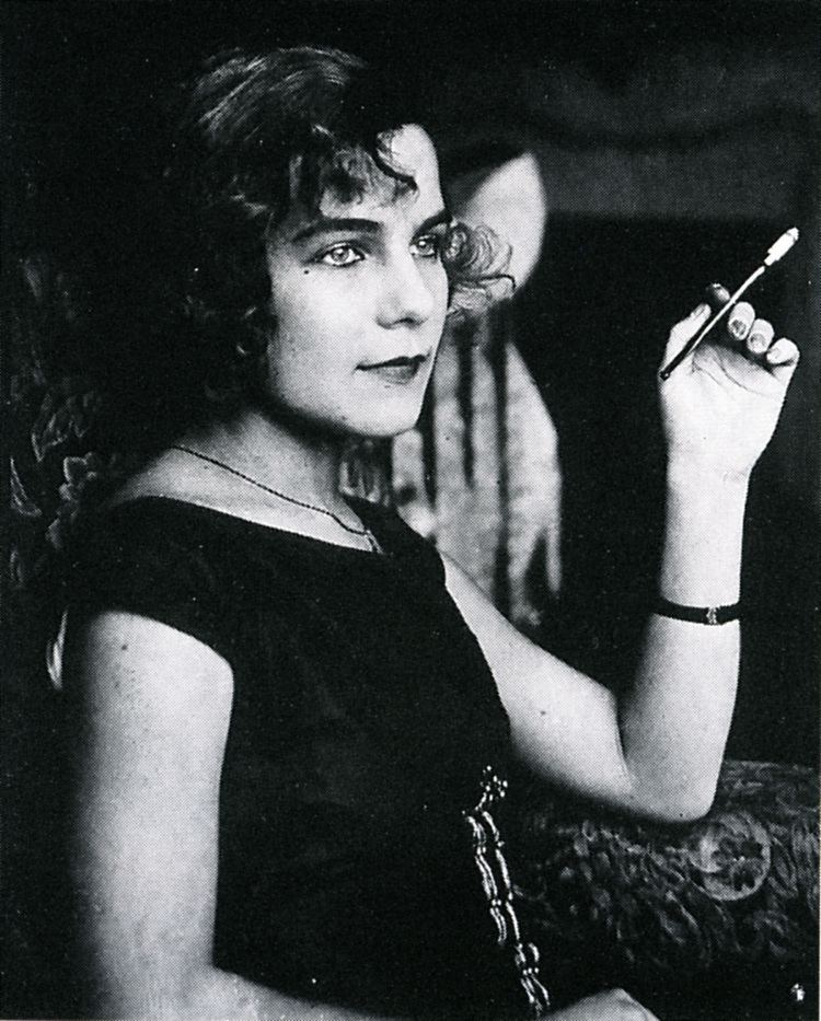 Maria Quisling while holding a pen wearing a dress (a black and white photo)
