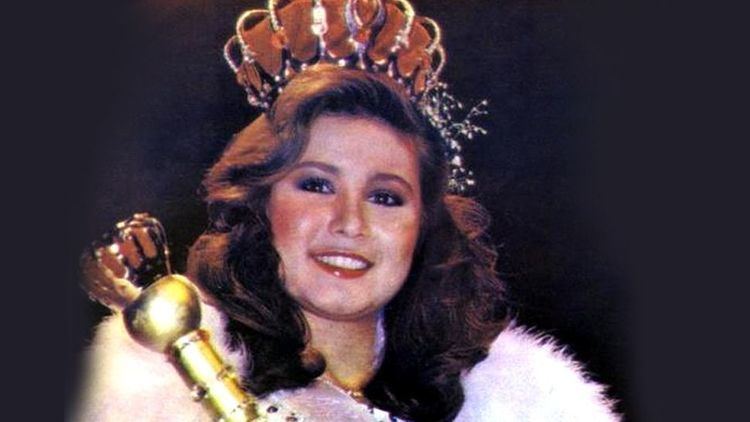 Maria Teresa Carlson smiling while holding a scepter and wearing a crown