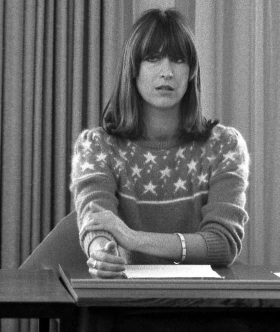 Marianne Bachmeier looking at something while sitting on the chair and wearing a bracelet and a sweater with a stars design
