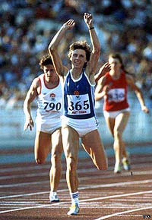 Marita Koch smiling during track and field competition while wearing a blue top and white shorts