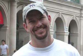 Mark Bingham smiling while wearing a gray cap and white t-shirt