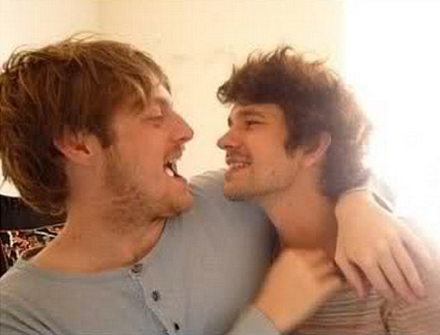Mark Bradshaw and Ben Whishaw are laughing while hugging each other. Both have thin beards and mustaches. Mark is wearing a gray long-sleeve shirt while Ben is wearing a striped shirt.