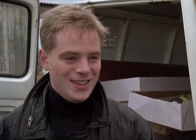Young Mark Farmer smiling while wearing a black jacket and black turtle-neck shirt
