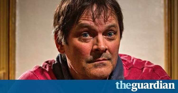 Mark Heap wearing a pink shirt with a collar.