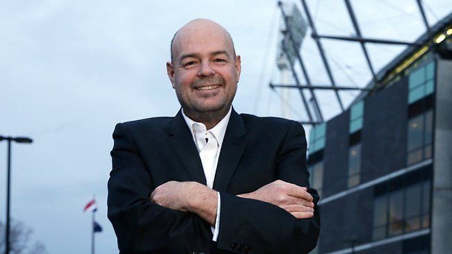 Mark Robinson smiling while wearing a black coat and white long sleeves