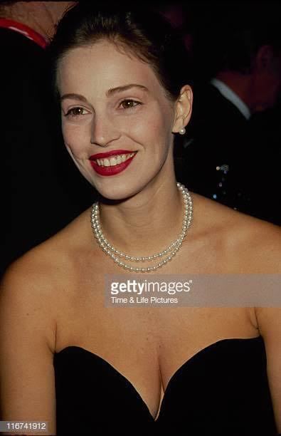 Marla Hanson smiling and wearing a black tube dress with a pearl necklace and earrings