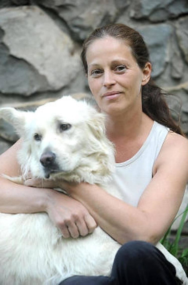 Marla Hanson smiling in a white shirt and holding her pet dog