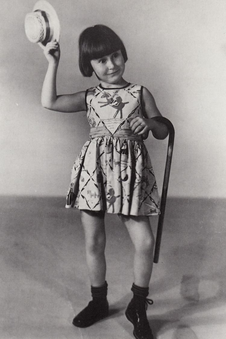 Mary Ann Jackson making a funny face while holding a hat and walking stick and wearing a sleeveless dress and shoes