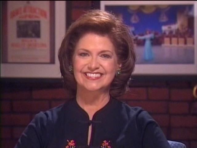 Mary Lou Metzger, in her short hair, smiles while wearing a black shirt
